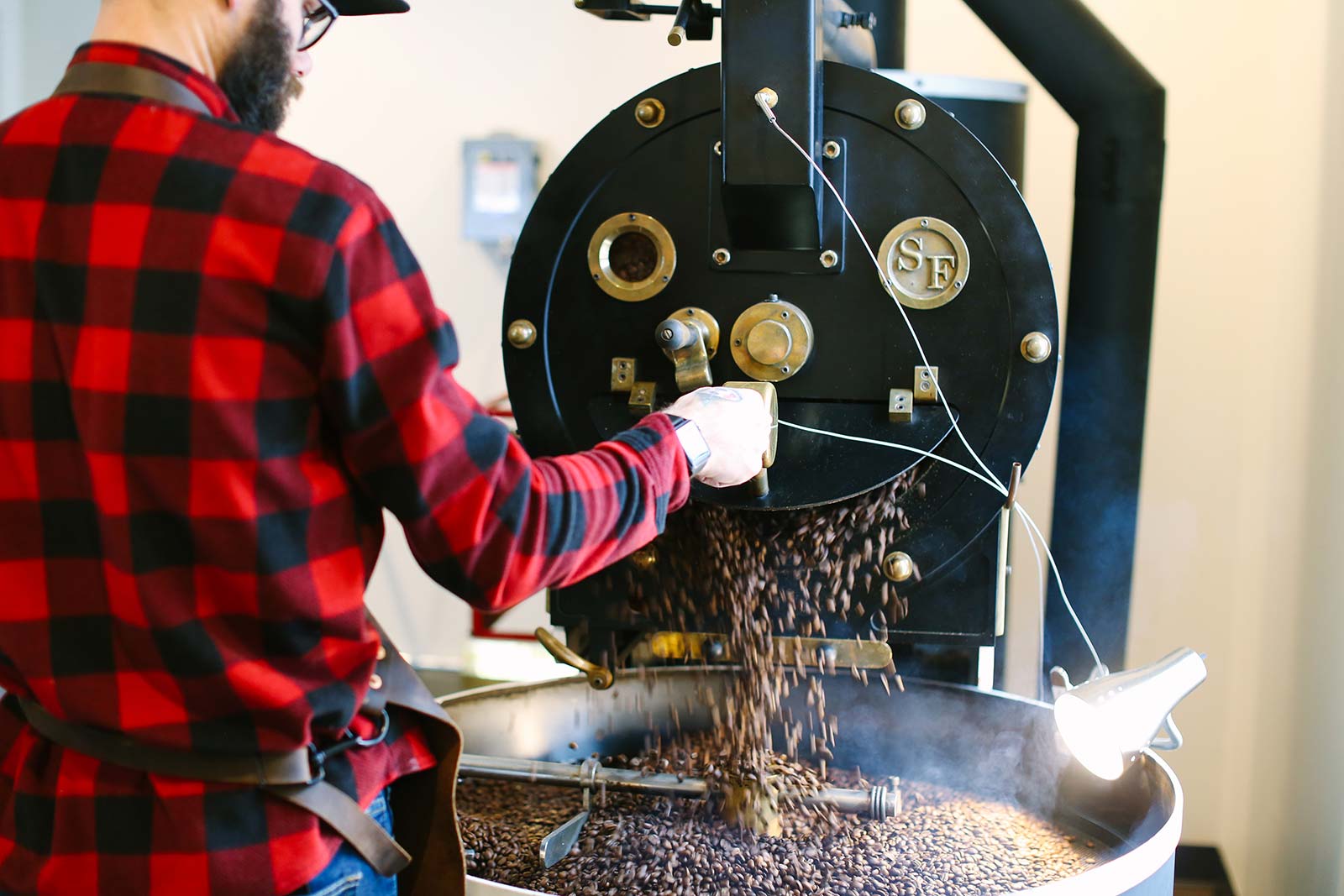 Indie Coffee Roasters - bearded man in a red and black plaid shirt grinding coffee